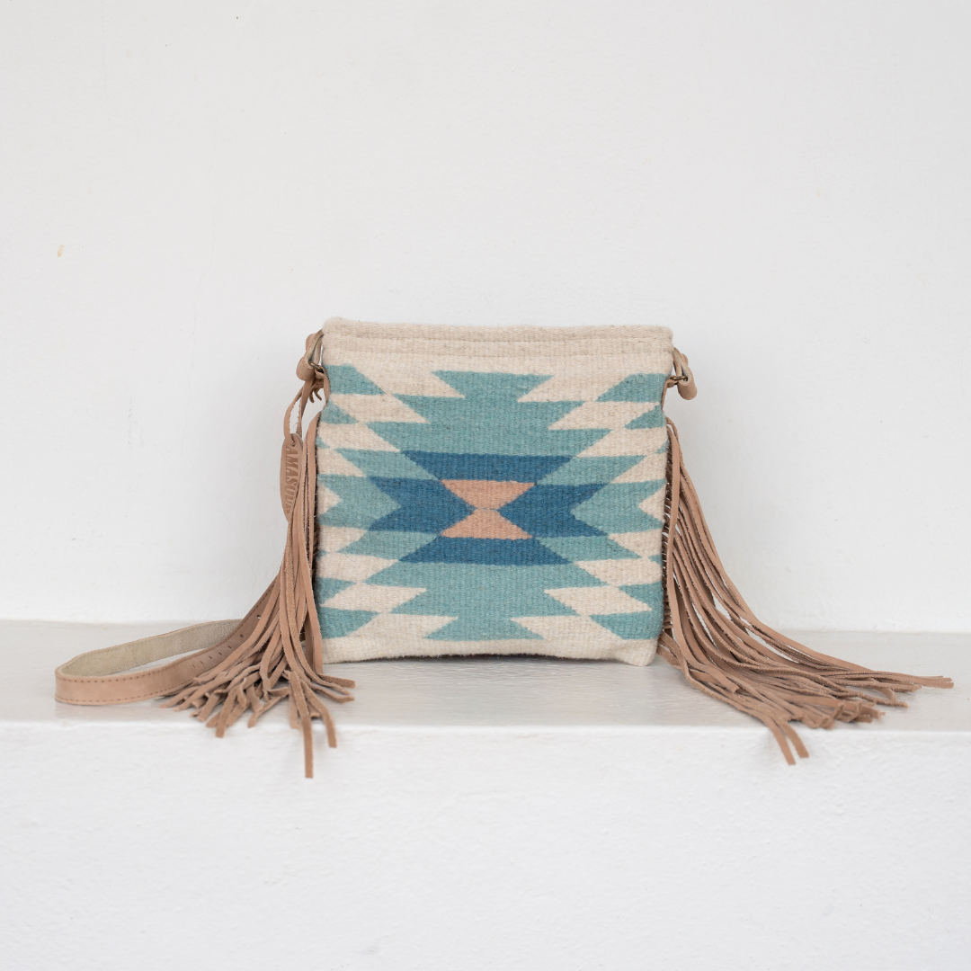 Handwoven fringe crossbody bag with abstract Zapotec diamond design in soft spring colors; features adjustable leather strap and two internal pockets