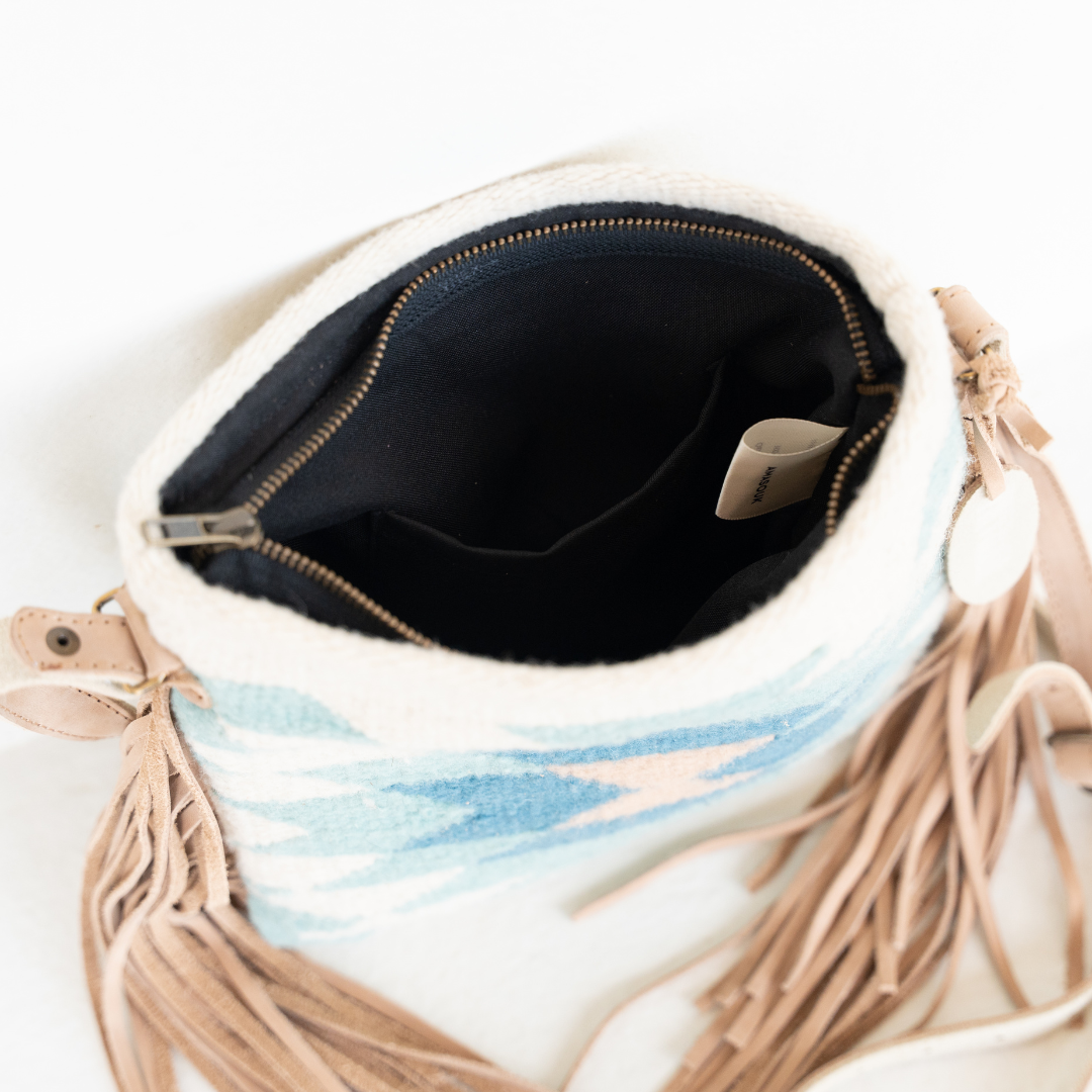 Interior view of handwoven fringe crossbody bag with abstract Zapotec diamond design in soft spring colors; features adjustable leather strap and two internal pockets