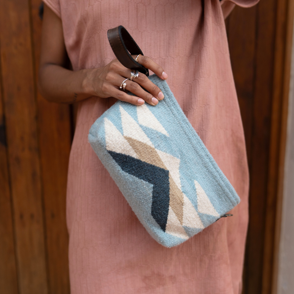 Fashionable woman with the AMASOUK Reflejos convertible clutch/wristlet/crossbody bag, handwoven in wool with a Zapotec pattern in stunning shades of blue. Perfect for day-to-night versatility.