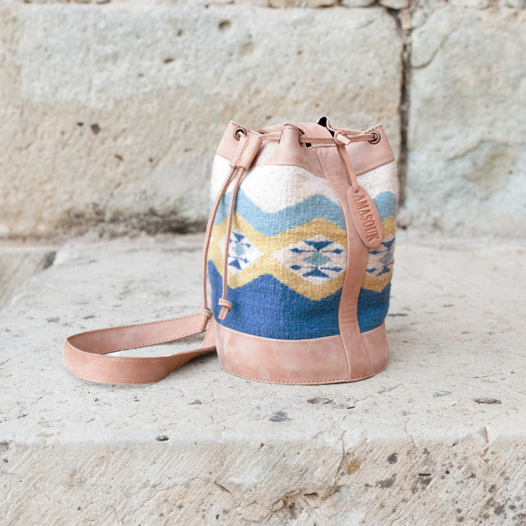 Colibrí Cinched Bucket Bag in handwoven wool and leather with green and blue Zapotec diamond and butterfly pattern, featuring an adjustable strap and cinched silhouette.