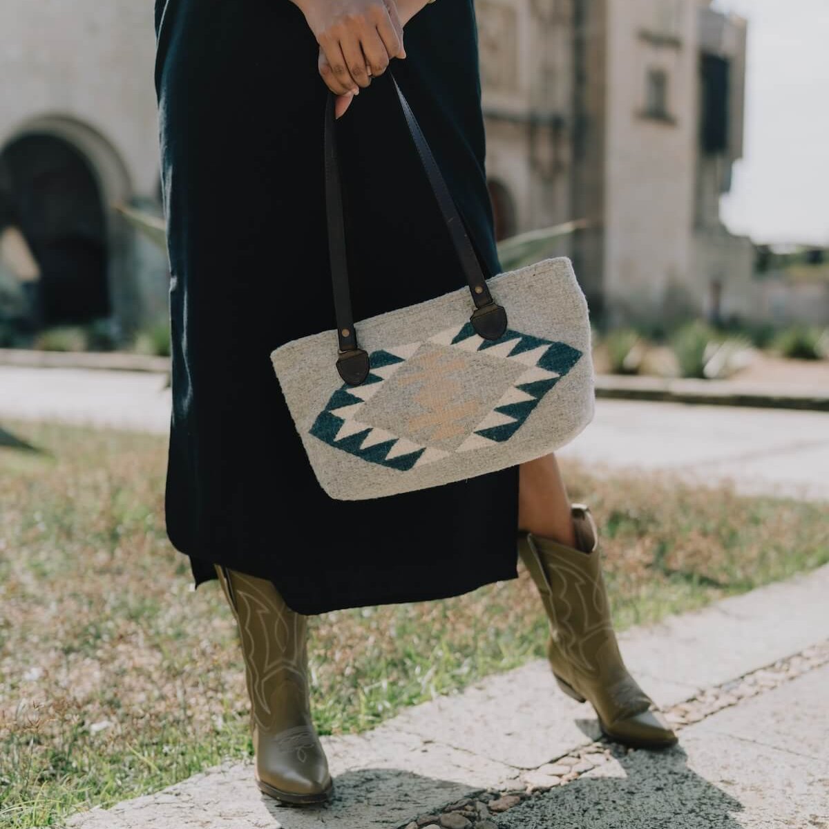 Woman with an AMASOUK handwoven wool purse in Dainzu pattern, featuring a Zapotec design in muted indigo blue, light cream, and honeyed accents. Ideal for any occasion.