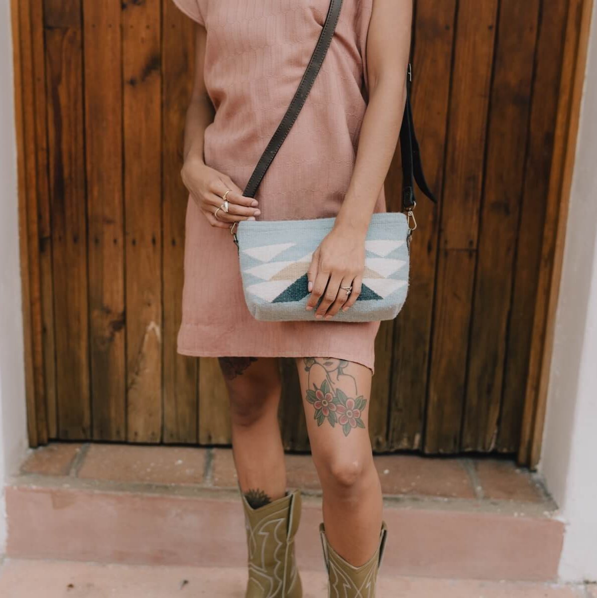 Chic woman styling the AMASOUK Reflejos handwoven wool 3-in-1 bag as a wristlet, clutch, or crossbody, featuring a Zapotec pattern in beautiful blue hues.