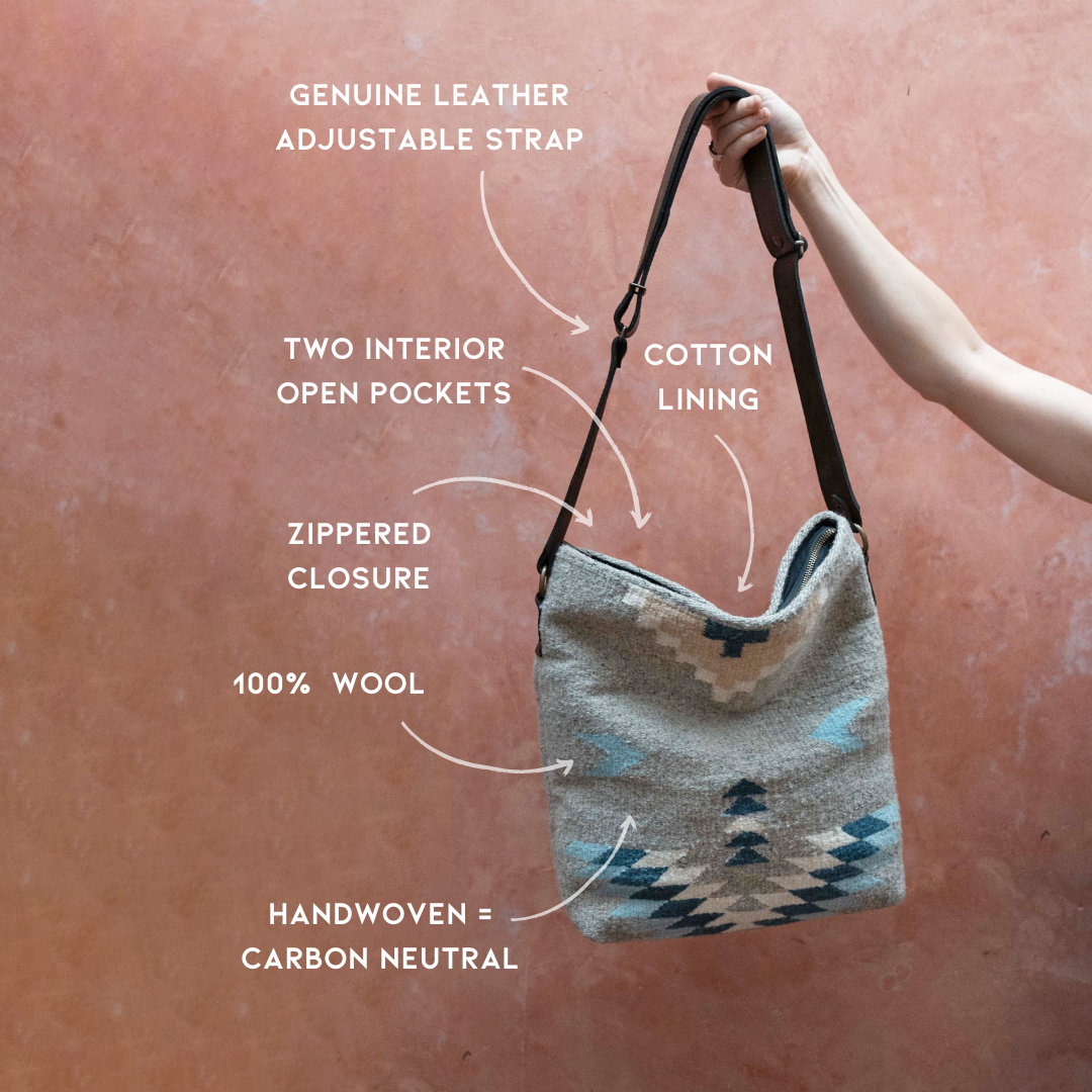 AMASOUK roomy handwoven wool Aguila Shoulder/Crossbody bag with a Zapotec pattern in blue, ivory, and honey on a gray backdrop. Ideal for any day-to-night occasion.