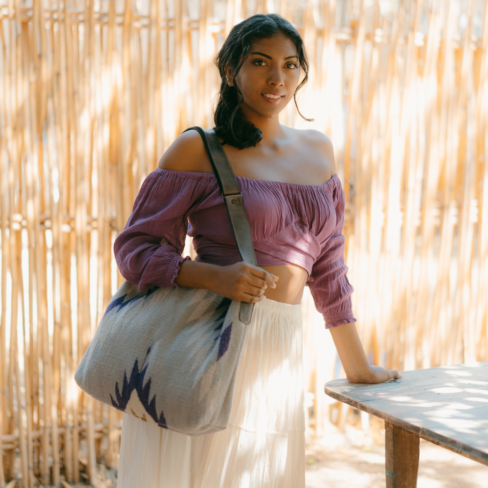 Fashionable woman with an AMASOUK handwoven wool Amethyst shoulder/crossbody bag, highlighted by shades of purple. Ideal for day-to-night versatility.