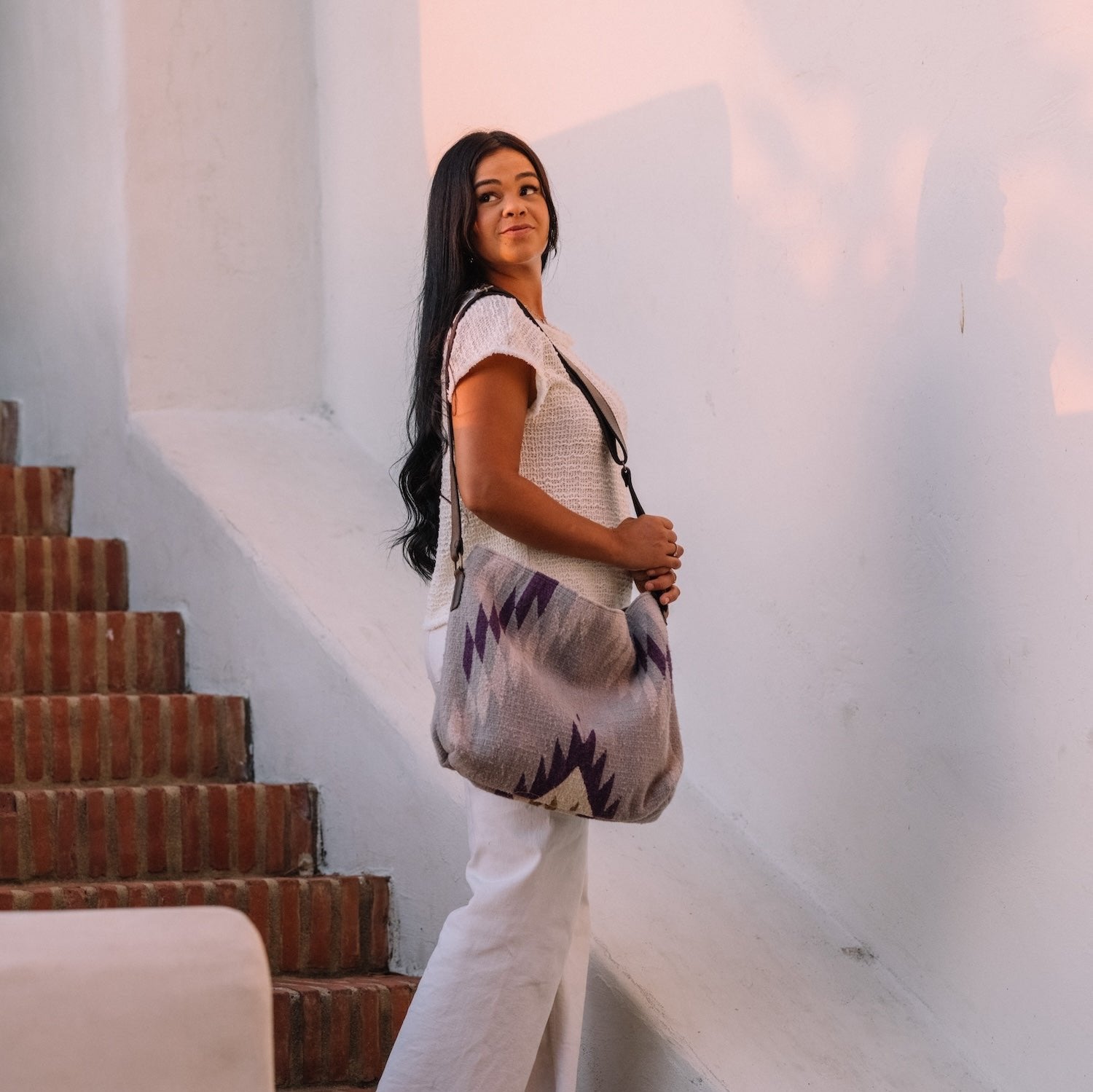 Woman with an AMASOUK handwoven wool Amethyst shoulder/crossbody bag in beautiful shades of purple. Perfect for adding a pop of color to everyday activities and evening events.