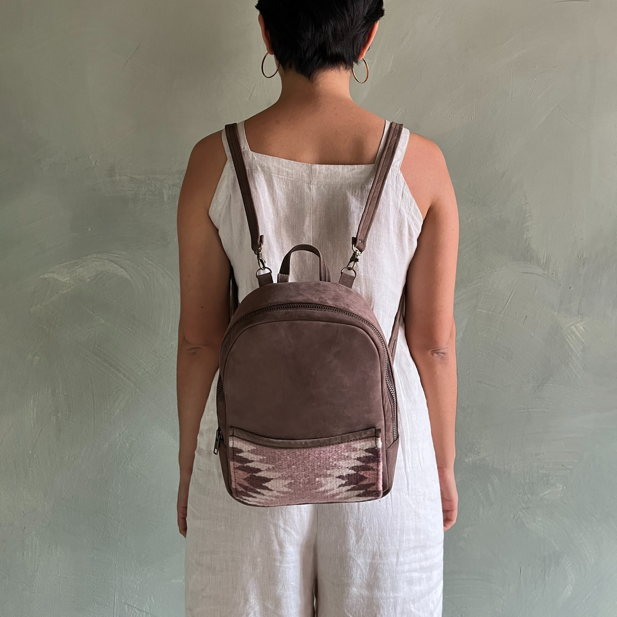Woman carrying the AMASOUK Aguila Mini Backpack, handcrafted from brown leather and sand and purple wool. A stylish and versatile accessory for daily use and casual outings.