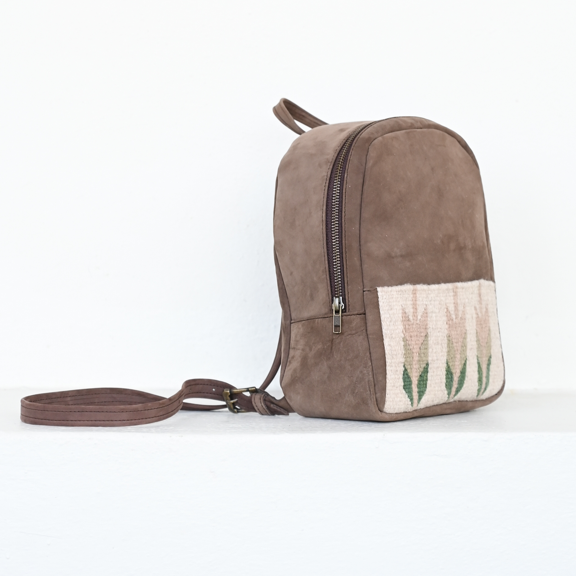 AMASOUK Arbol Mini Backpack made from high-quality leather and wool, with rich brown leather and light green and cream wool accents. A chic and versatile accessory.
