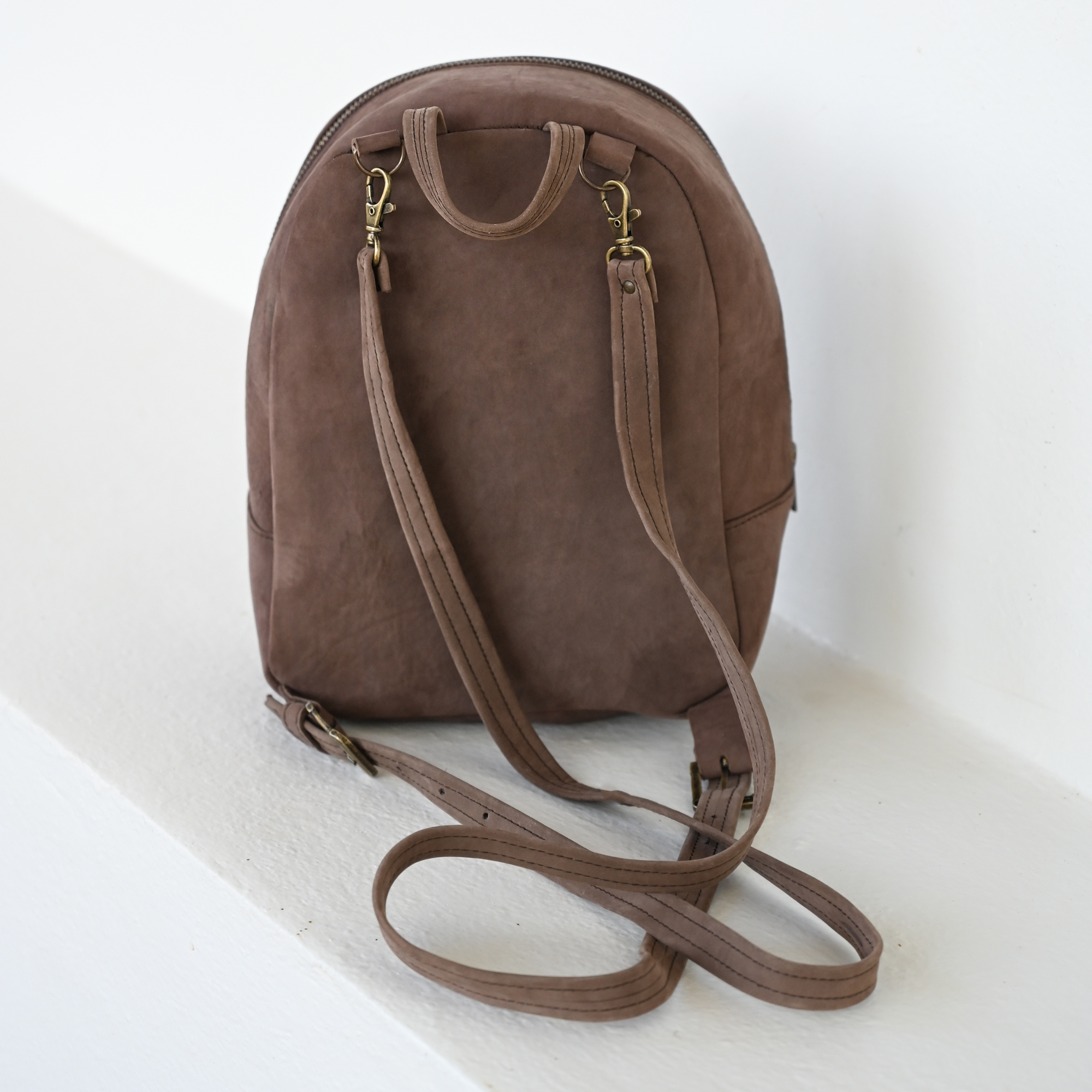 Back view of Handcrafted AMASOUK Raiz Mini Backpack, featuring brown leather accents and burgundy and cream wool with a Zapotec pattern. A chic, functional accessory.
