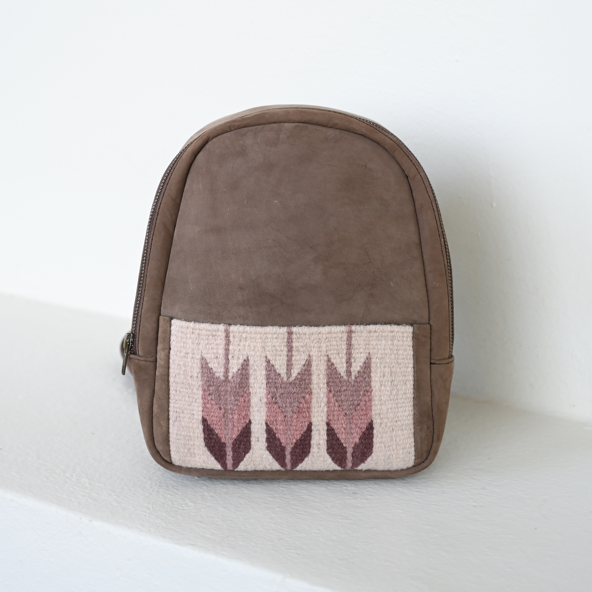 Compact AMASOUK Raiz Mini Backpack made with brown leather and burgundy and cream handwoven wool, showcasing a timeless Zapotec pattern.