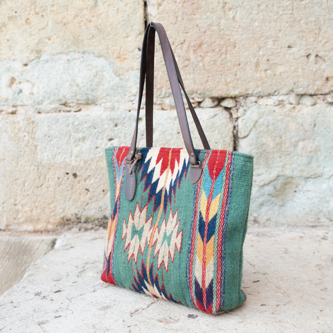 Handwoven wool tote bag in green and bold colors with Zapotec patterns, leather shoulder straps, and relaxed shape, roomy and ideal for everyday use.