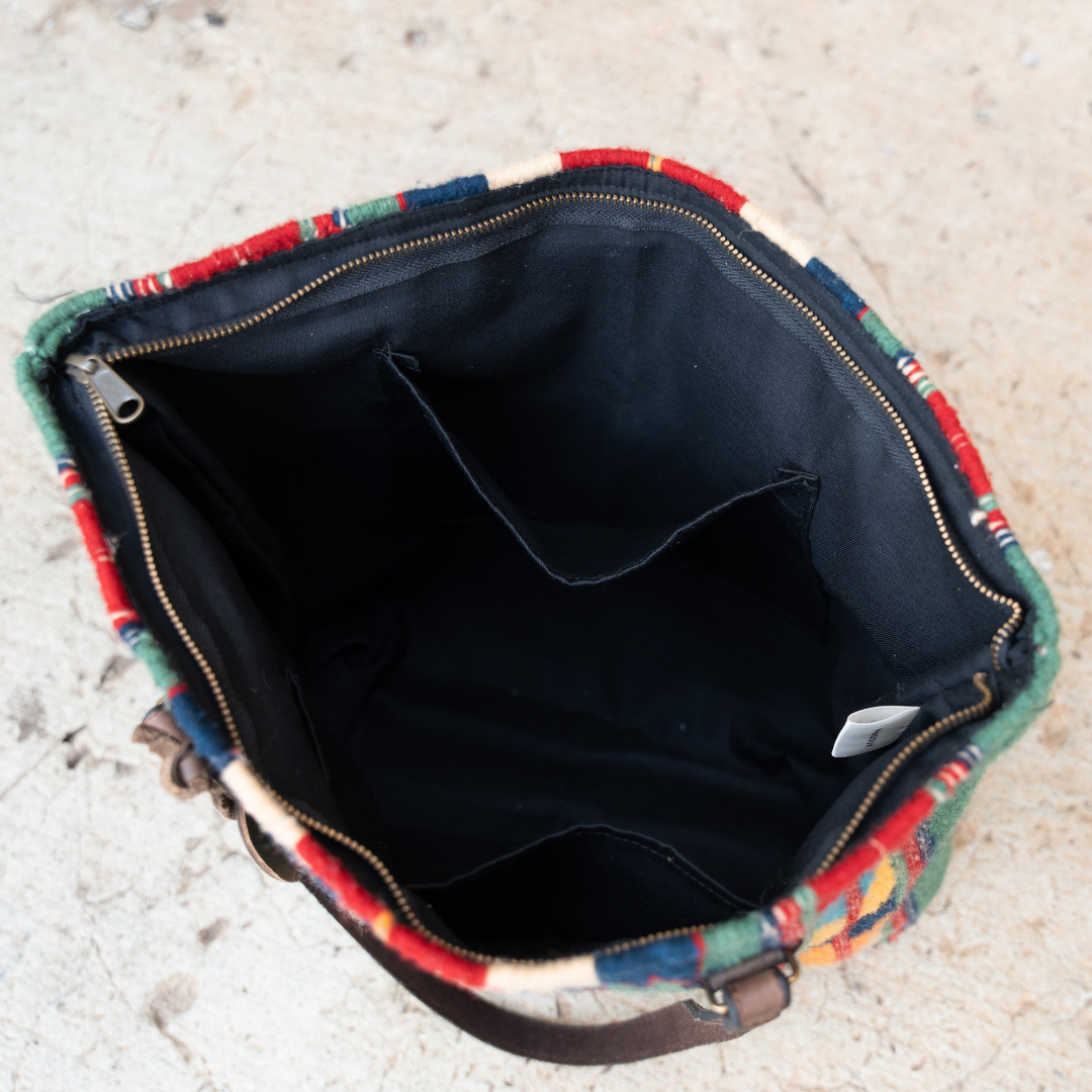 Interior view of cotton lining and open pockets of handwoven wool tote bag in green and bold colors with Zapotec patterns, leather shoulder straps, and relaxed shape, roomy and ideal for everyday use.