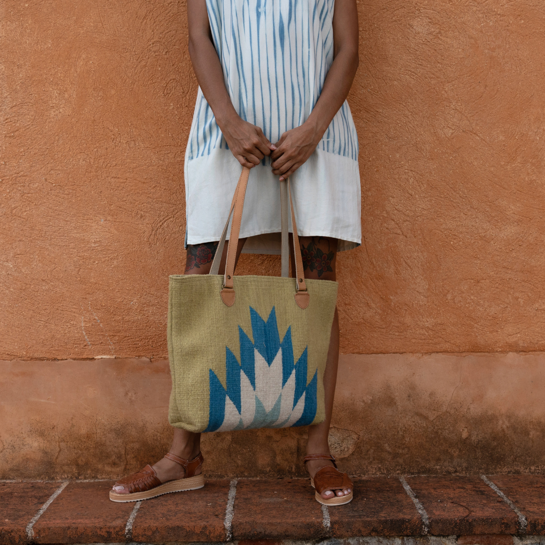 Woman carrying Zapotec handwoven tote bag with blue and green lightning design, leather straps, and interior pocket; spacious and stylish for everyday use