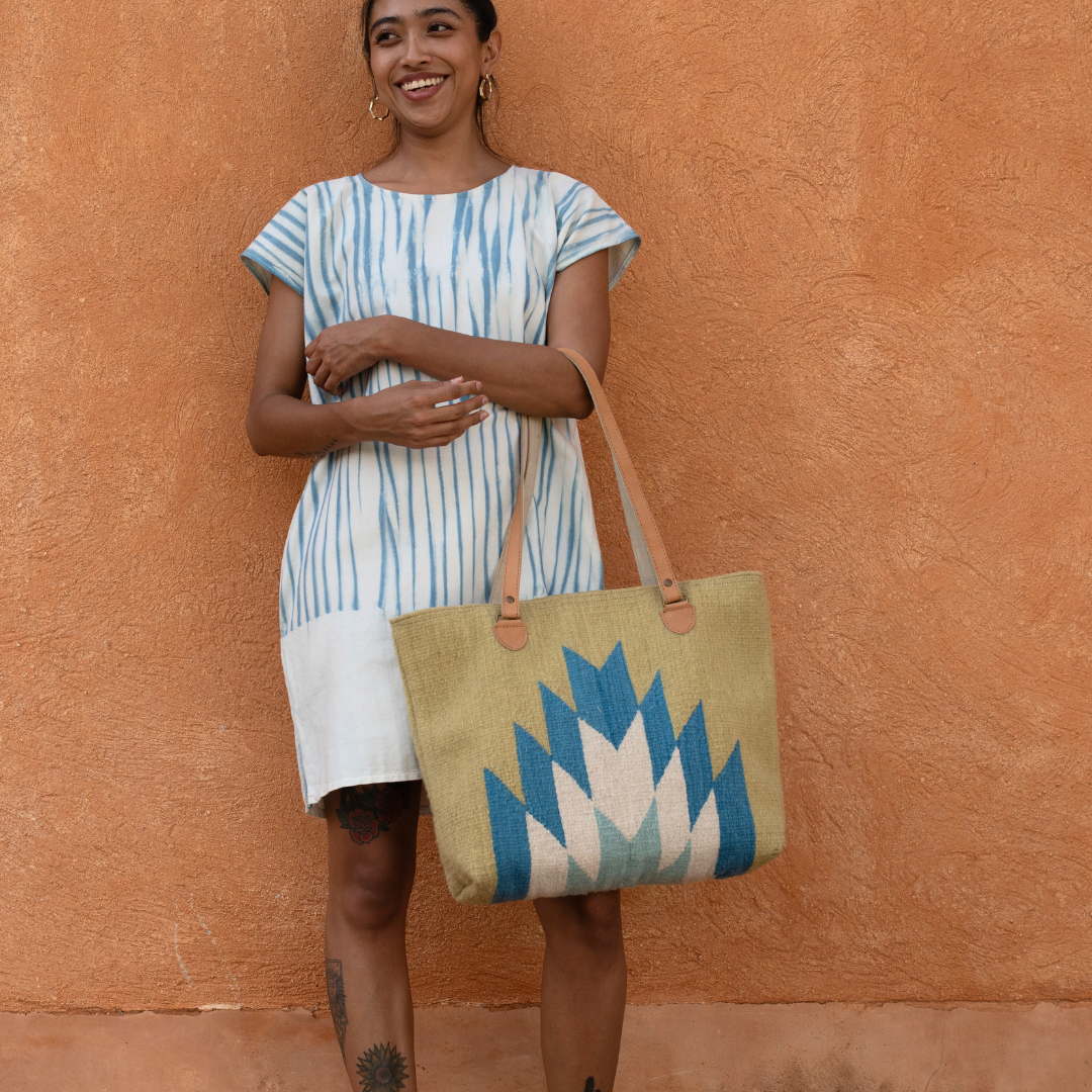 Woman carrying Zapotec handwoven tote bag with blue and green lightning design, leather straps, and interior pocket; spacious and stylish for everyday use