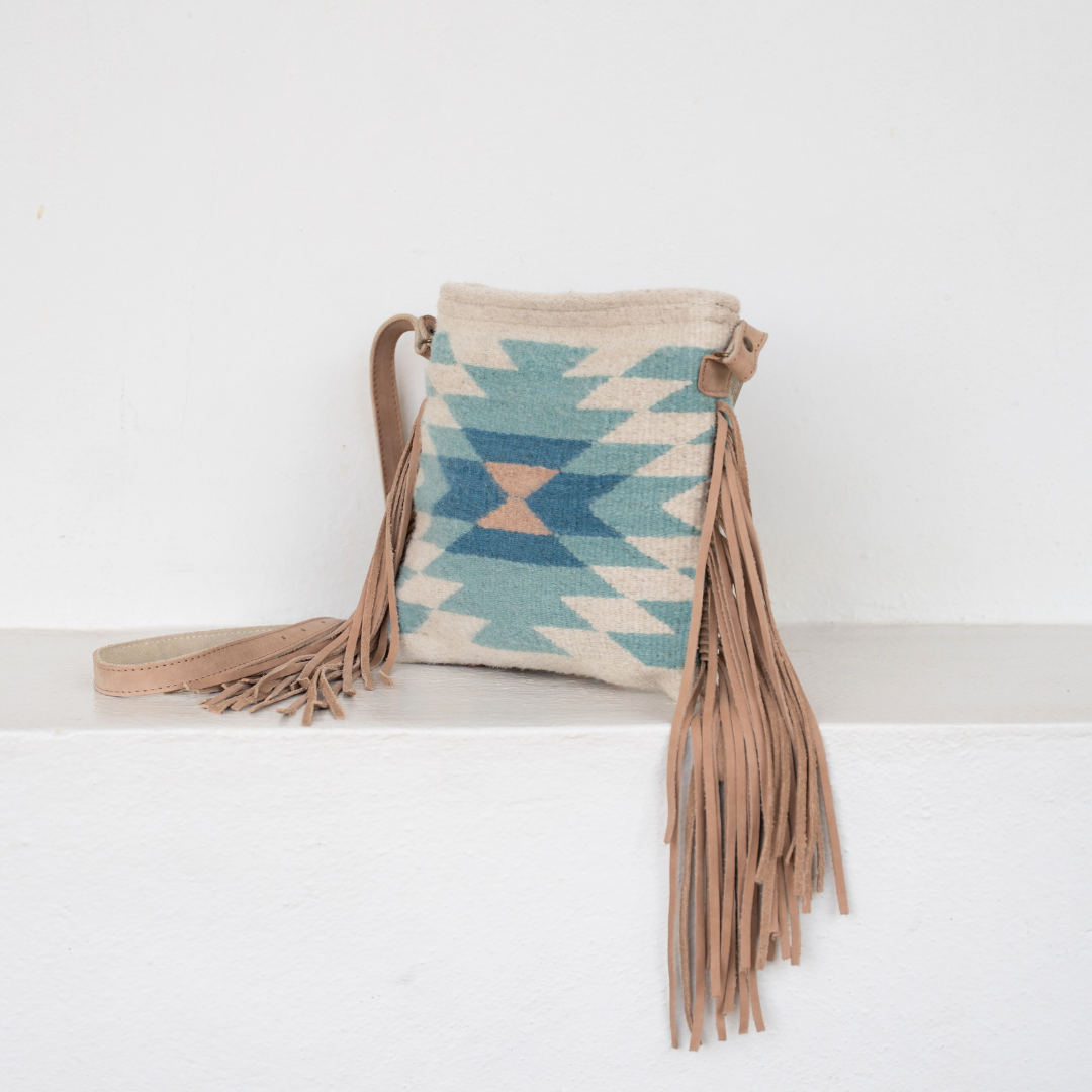 Handwoven fringe crossbody bag with abstract Zapotec diamond design in soft spring colors; features adjustable leather strap and two internal pockets