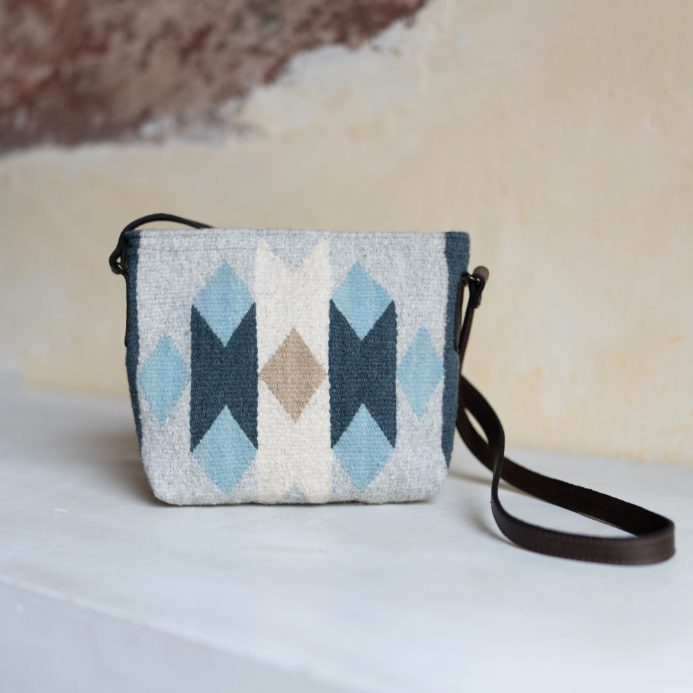 AMASOUK handwoven wool Espejos Crossbody with dark brown leather strap, featuring a Zapotec pattern in blue, heather gray, and ivory. Artisan-crafted and perfect for day-to-night style.