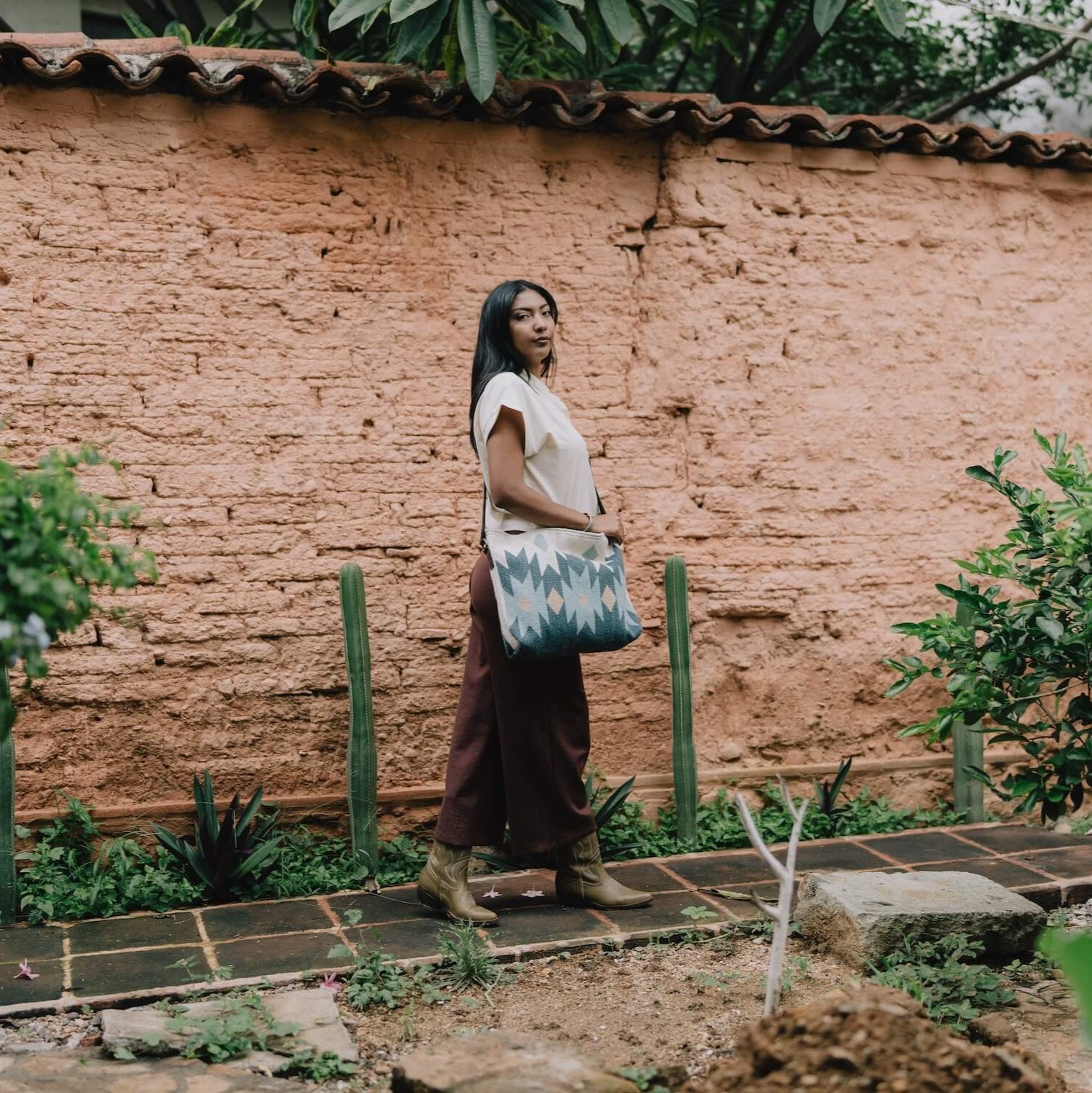 Fashionable woman with an AMASOUK handwoven wool Alcala Shoulder/Crossbody Bag, showcasing blue, ivory, and honey tones. Perfect for day-to-night versatility.