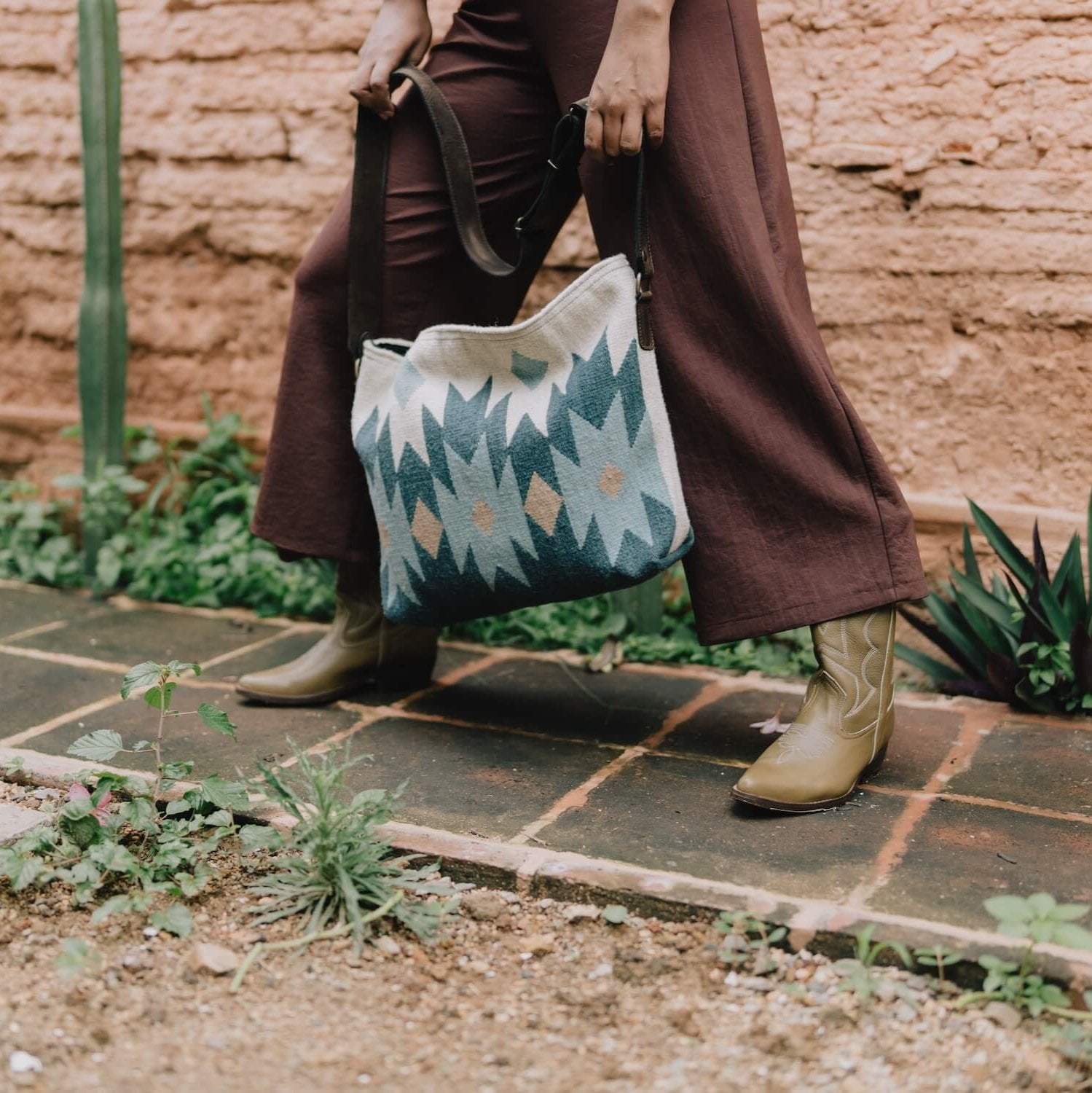 Woman with an AMASOUK handwoven wool Alcala Shoulder/Crossbody Bag in blue, ivory, and honey colors. Stylish and practical for daily use and evening events.