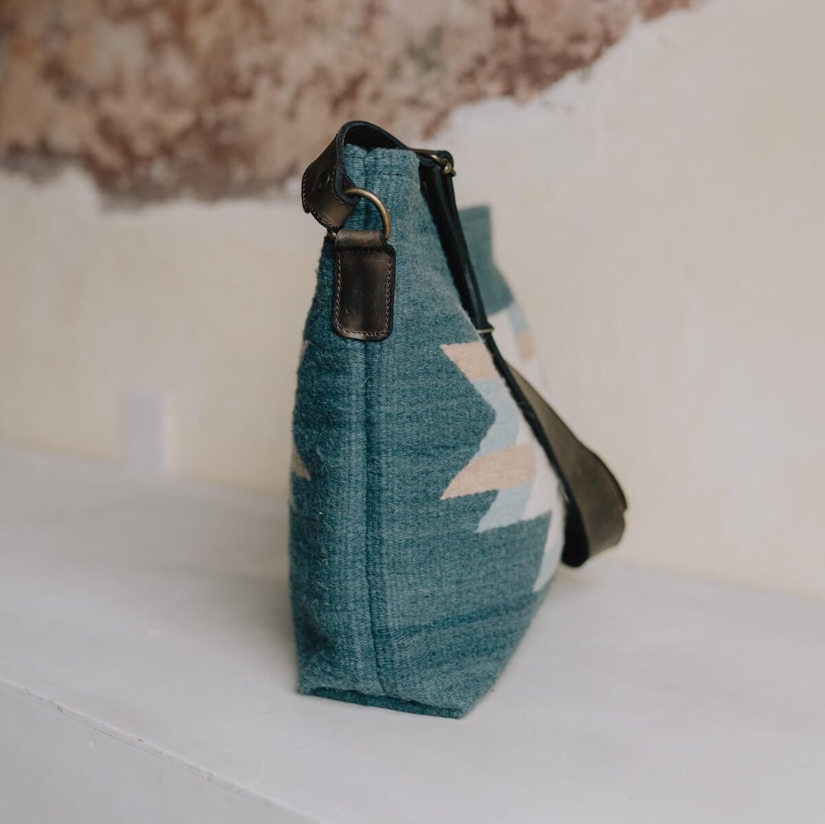 Side View AMASOUK handwoven wool Solyagaua convertible shoulder/crossbody bag in a blend of ocean blue, neutral ivory, and golden honey. This bag showcases a detailed Zapotec pattern, ideal for any occasion.