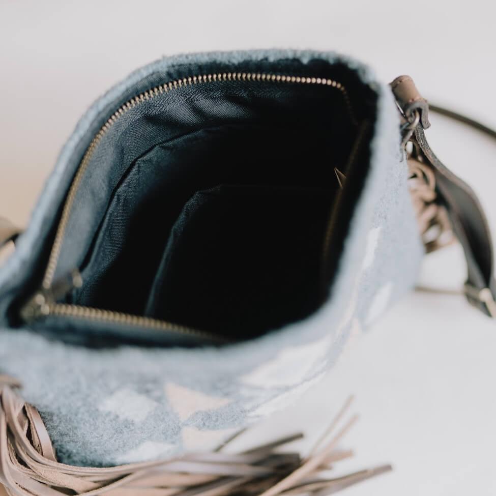 Interior view of Handwoven AMASOUK Jalisco Fringe Crossbody bag with a dark brown leather strap and fringe detailing, showcasing wool in blue, heather gray, and honey. Festive and stylish with Zapotec patterns.