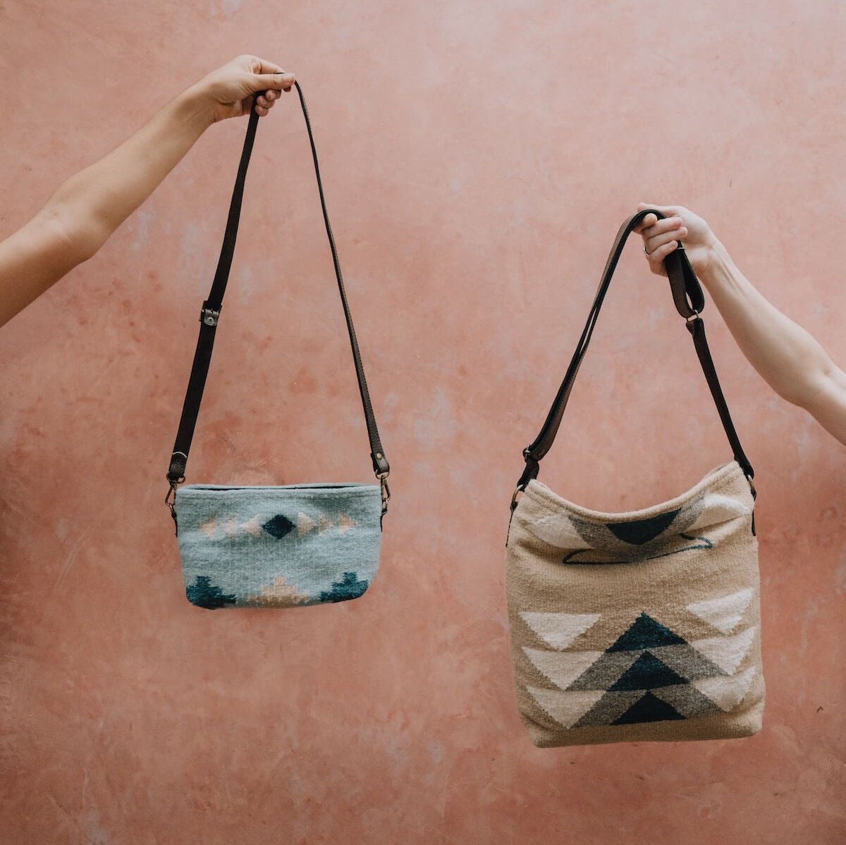 Elegant AMASOUK handwoven wool and leather Pueblo convertible shoulder/crossbody bag, showcasing a mix of navy, slate, and ivory tones on a sand-colored base. The ideal accessory for day-to-night outings.