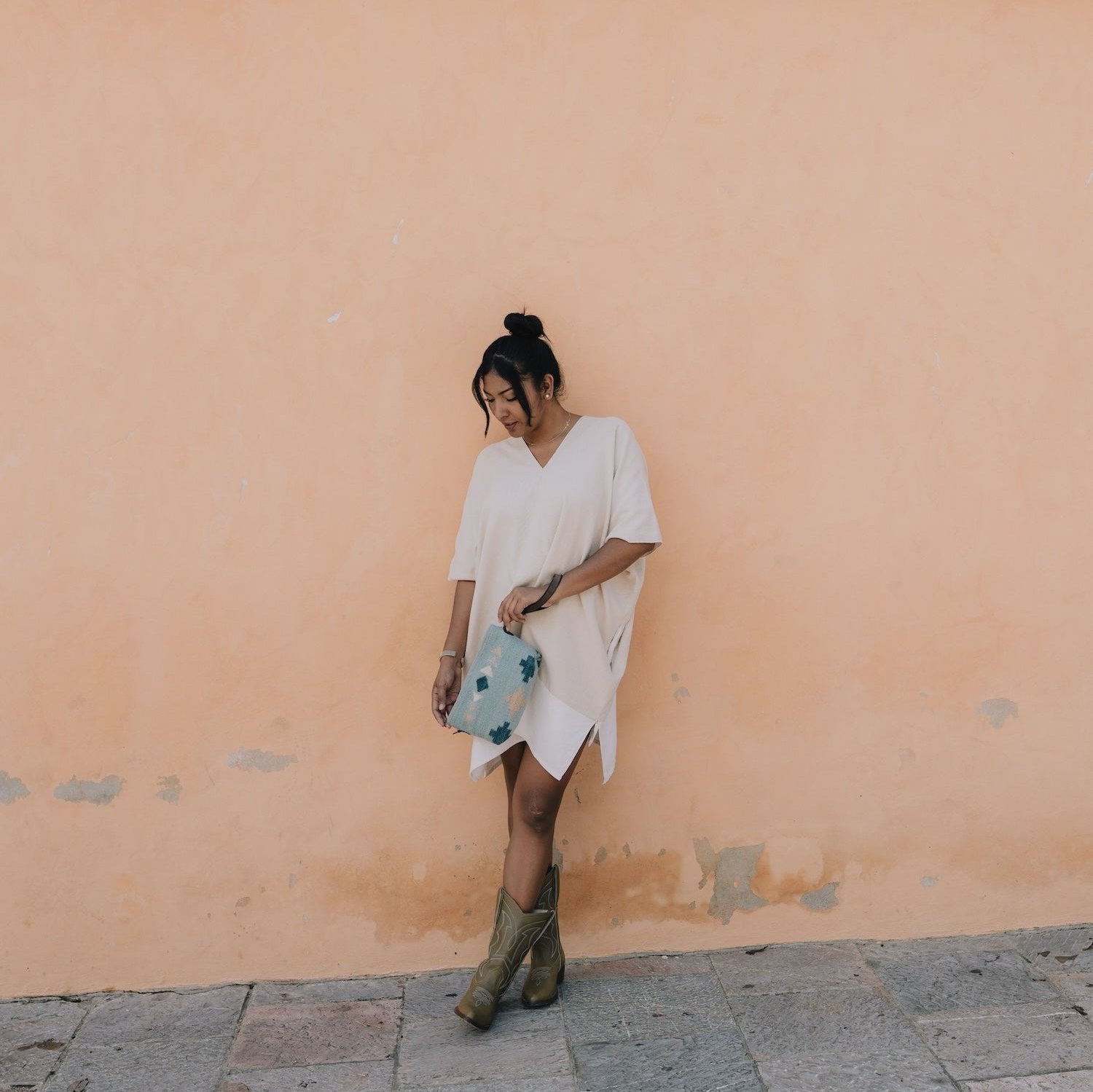 Woman with the AMASOUK Cielito Convertible Clutch/Wristlet/Crossbody Bag, crafted from handwoven wool with a Zapotec pattern in blue. Ideal for versatile day-to-night styling.