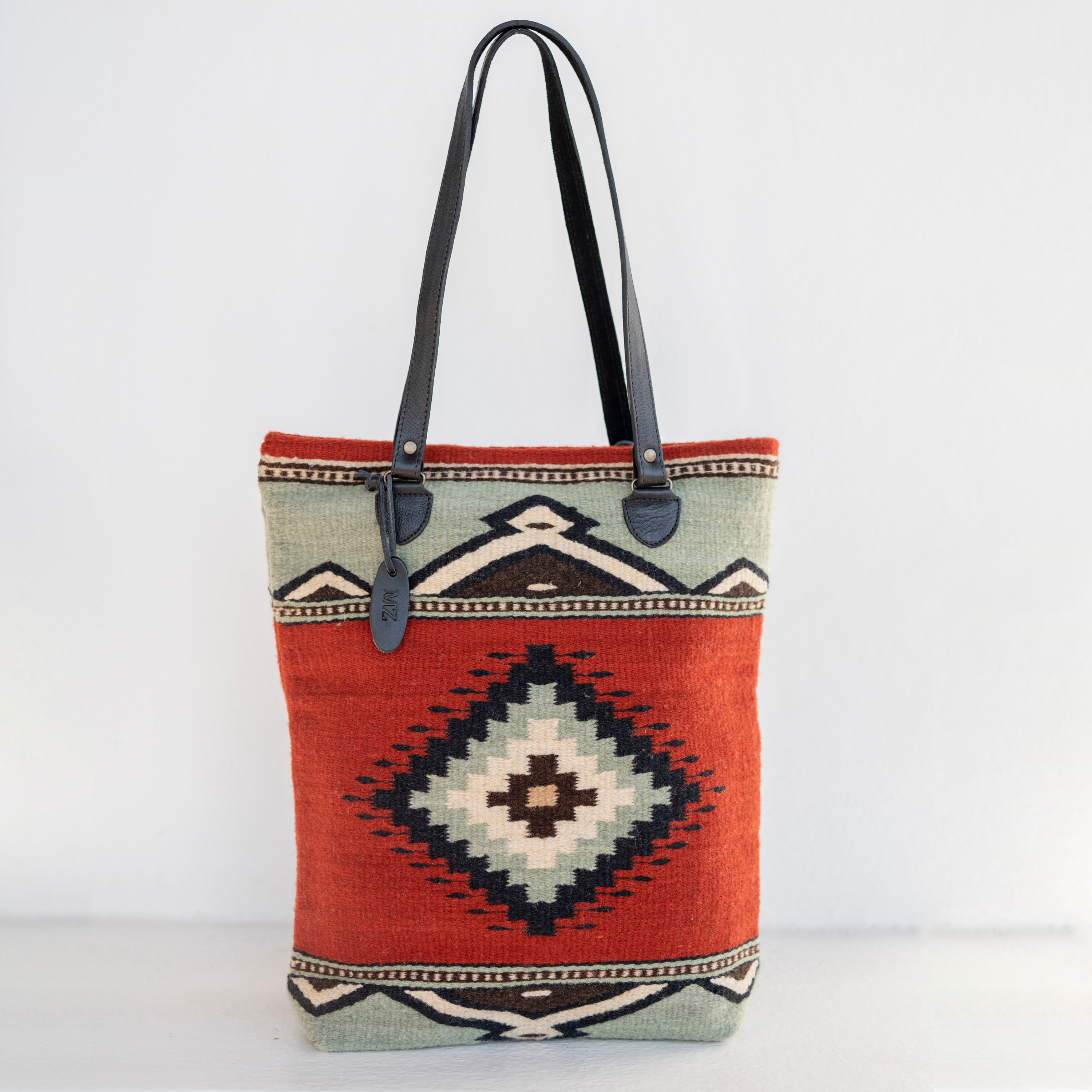 AMASOUK handwoven wool tote bag with Adobe + Azul name, featuring a Zapotec pattern in rich adobe red and soft mint green. Stylish and versatile for daily use and evening outings