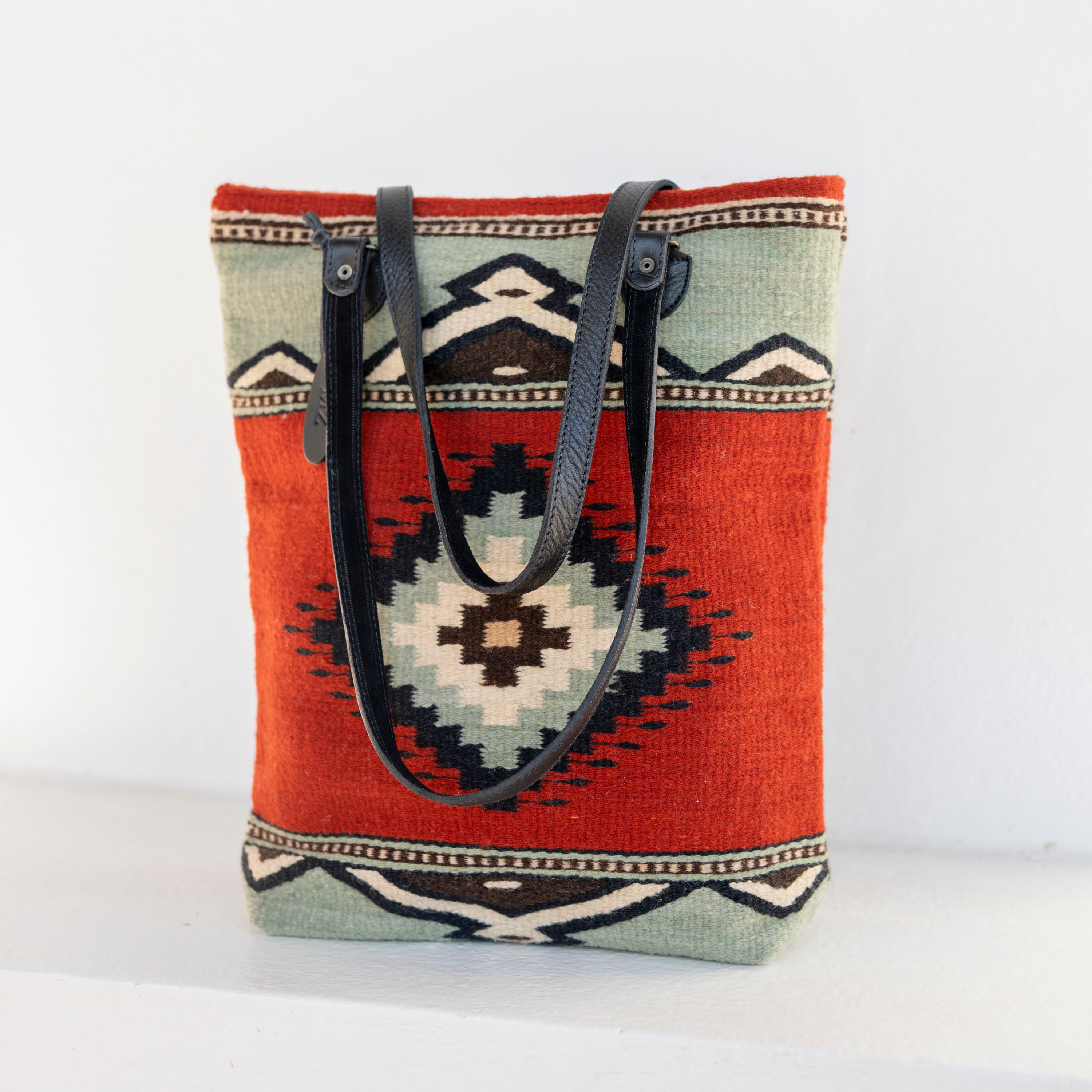 AMASOUK roomy handwoven wool tote with Adobe + Azul name, adorned with a Zapotec pattern in adobe red and mint green. Ideal for any day-to-night occasion.