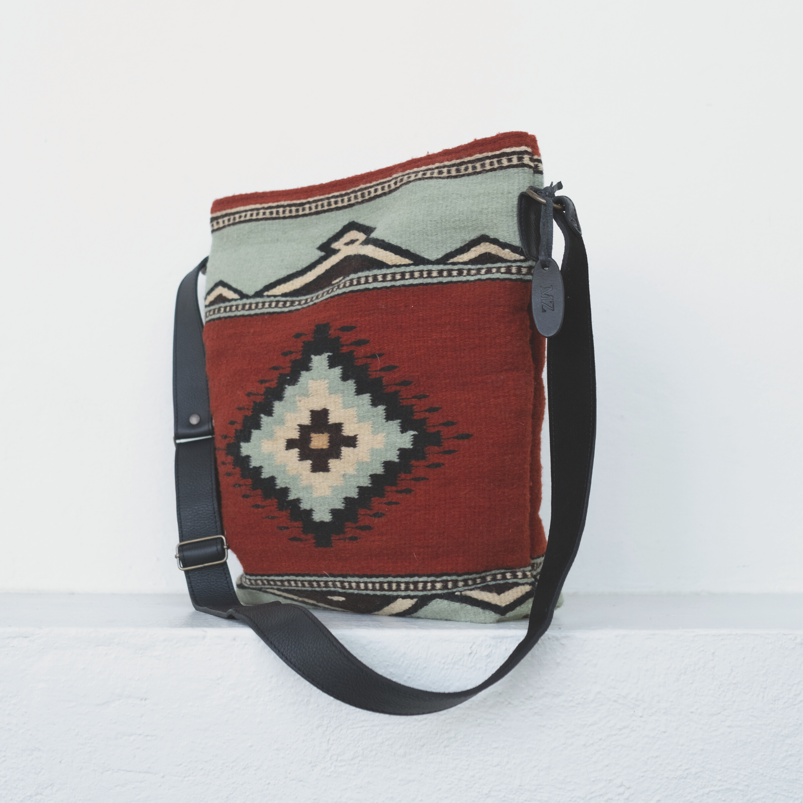 AMASOUK handwoven wool convertible shoulder/crossbody bag with Adobe + Azul design, showcasing a Zapotec pattern in adobe red and mint green. Perfect for errands, travel, or a night out.