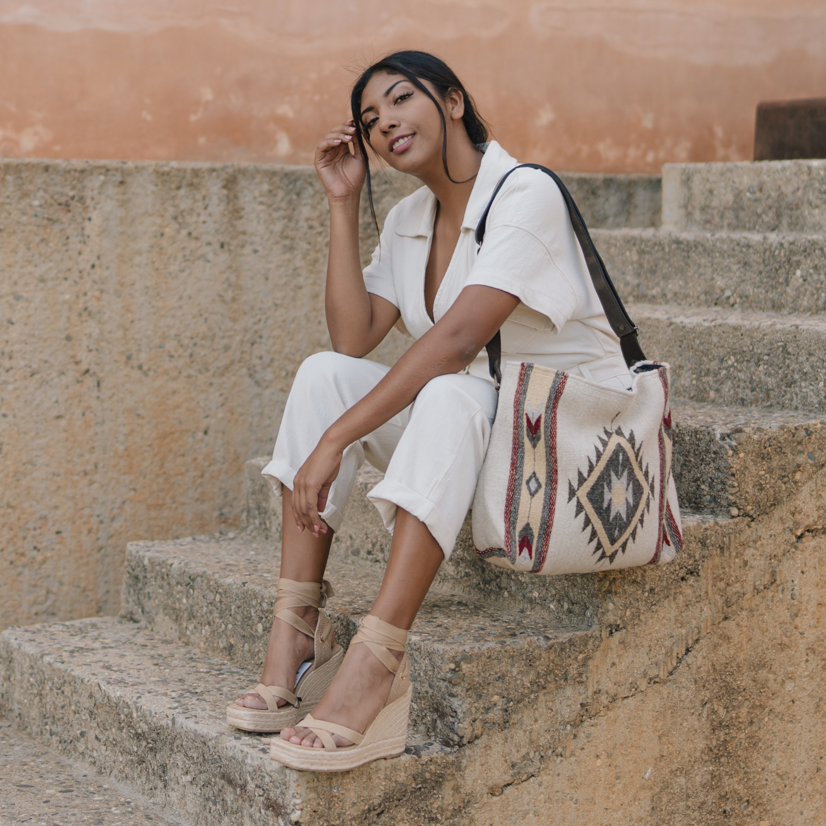 Fashionable woman with an AMASOUK handwoven wool Snowflake convertible shoulder/crossbody bag in a berry red hue with warm gold and subtle gray details on natural cream wool. Ideal for day-to-night versatility.