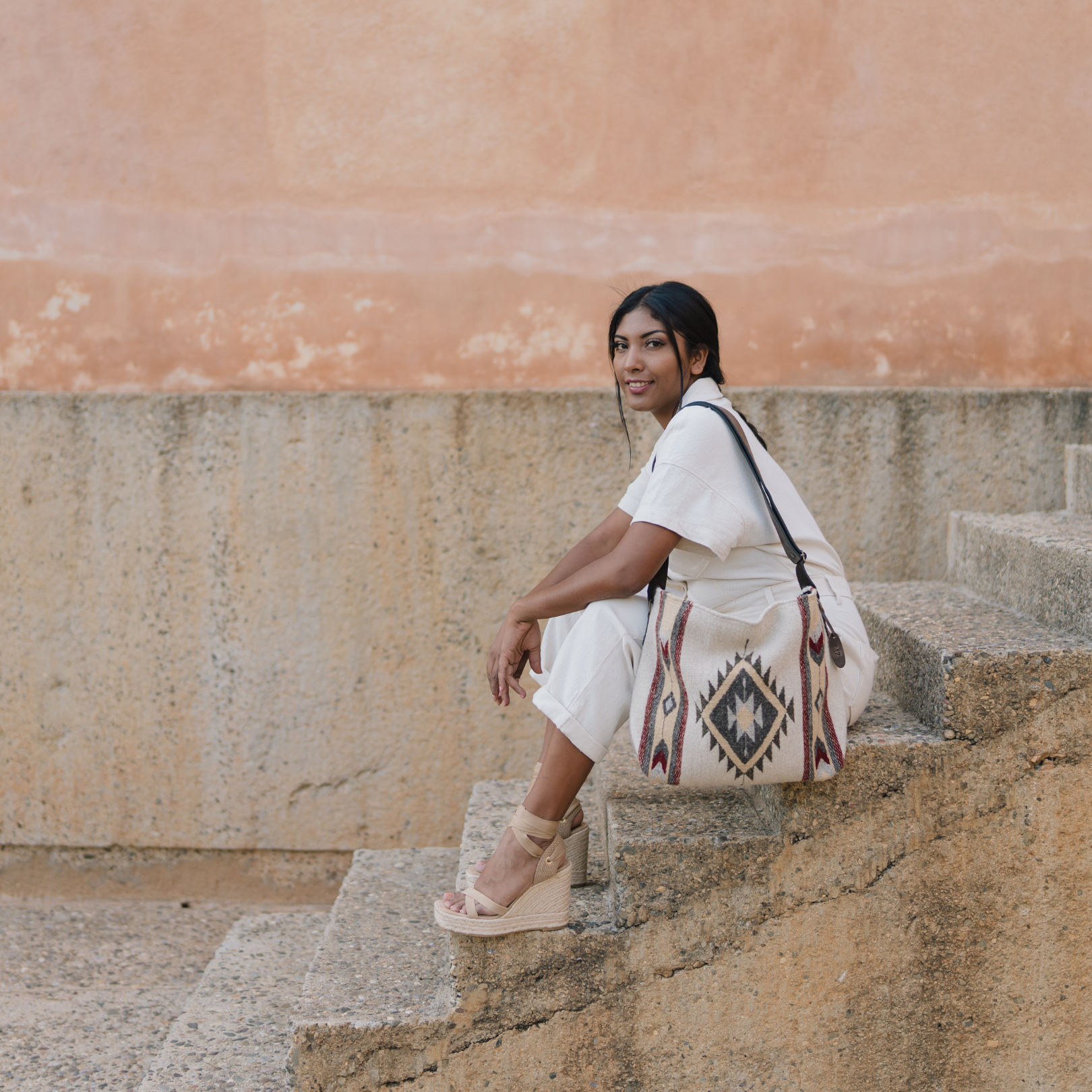 Woman with an AMASOUK handwoven wool Snowflake convertible shoulder/crossbody bag featuring a rich crimson shade, buttery gold, and soft gray on a natural cream wool base. Perfect for everyday activities and evening events.