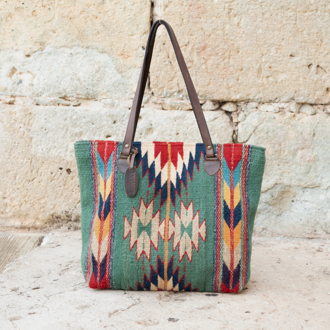 Handwoven wool tote bag in green and bold colors with Zapotec patterns, leather shoulder straps, and relaxed shape, roomy and ideal for everyday use. 