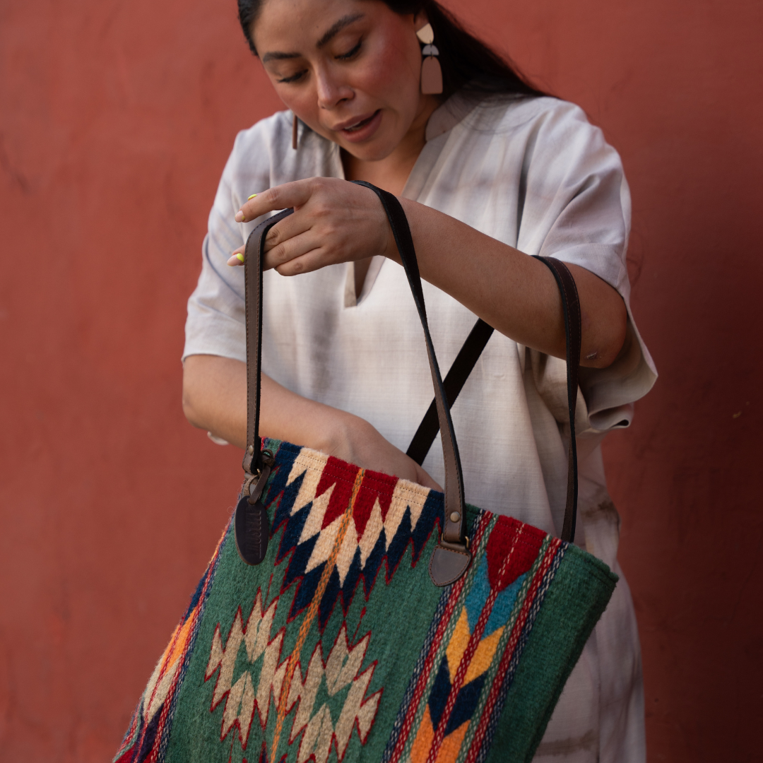Woman carrying Handwoven wool tote bag in green and bold colors with Zapotec patterns, leather shoulder straps, and relaxed shape, roomy and ideal for everyday use. 